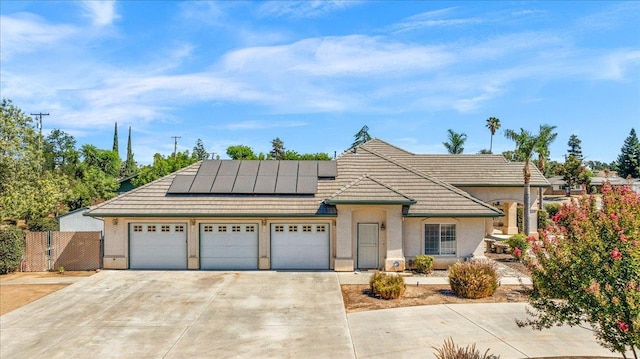 431 S Fowler Ave, Fresno, CA 93727 - view of front facade with a garage, stucco siding, roof mounted solar panels, and driveway