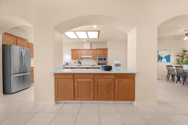 431 S Fowler Ave, Fresno, CA 93727 - kitchen with stainless steel appliances, light countertops, arched walkways, light tile patterned flooring, and under cabinet range hood
