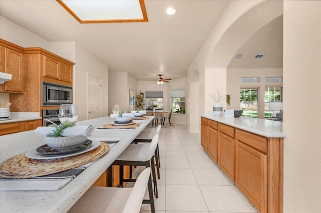 431 S Fowler Ave, Fresno, CA 93727 - kitchen with appliances with stainless steel finishes, light countertops, light tile patterned floors, a kitchen bar, and arched walkways