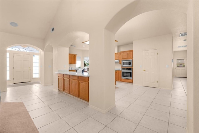 431 S Fowler Ave, Fresno, CA 93727 - kitchen with appliances with stainless steel finishes, light tile patterned floors, light countertops, arched walkways, and brown cabinets
