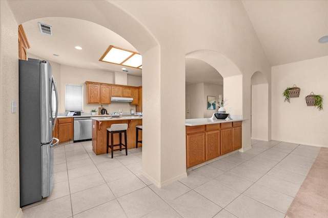 431 S Fowler Ave, Fresno, CA 93727 - kitchen featuring appliances with stainless steel finishes, light tile patterned floors, light countertops, under cabinet range hood, and a kitchen breakfast bar