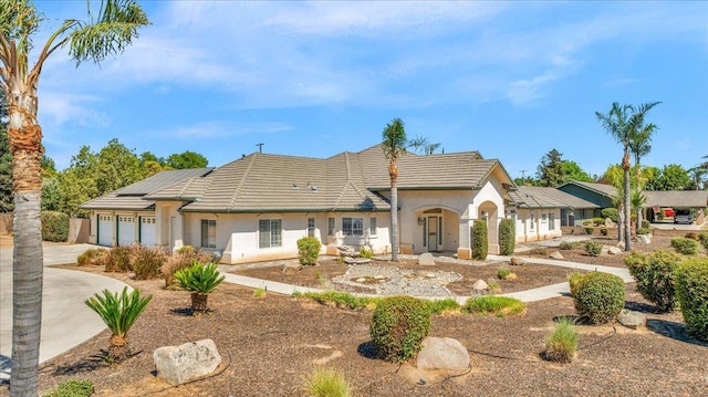 431 S Fowler Ave, Fresno, CA 93727 - view of front of home with a garage, driveway, roof mounted solar panels, a tile roof, and stucco siding