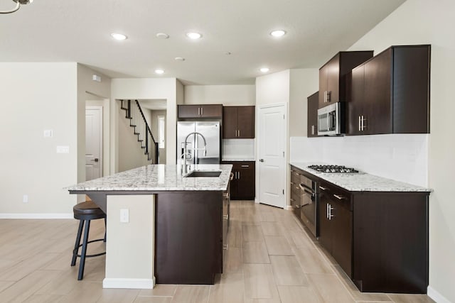 503 Cathedral Ct S, Madera, CA 93636 - kitchen featuring stainless steel appliances, a kitchen breakfast bar, dark brown cabinets, recessed lighting, and an island with sink