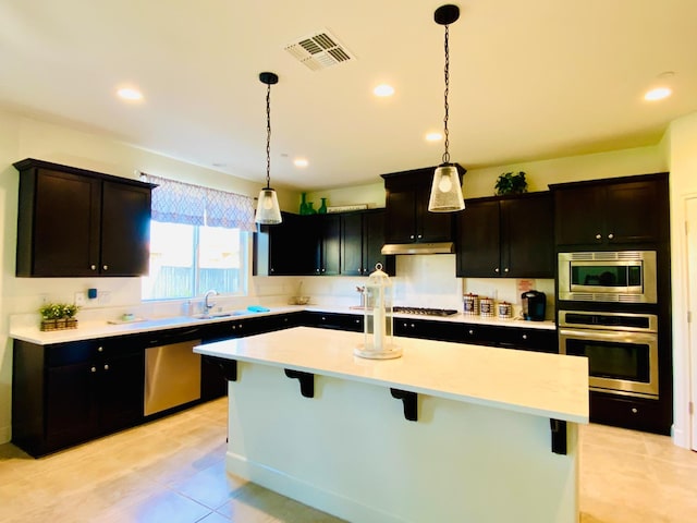 578 S Alpine Way S, Madera, CA 93636 - kitchen with appliances with stainless steel finishes, a kitchen island, a breakfast bar, light countertops, and decorative light fixtures