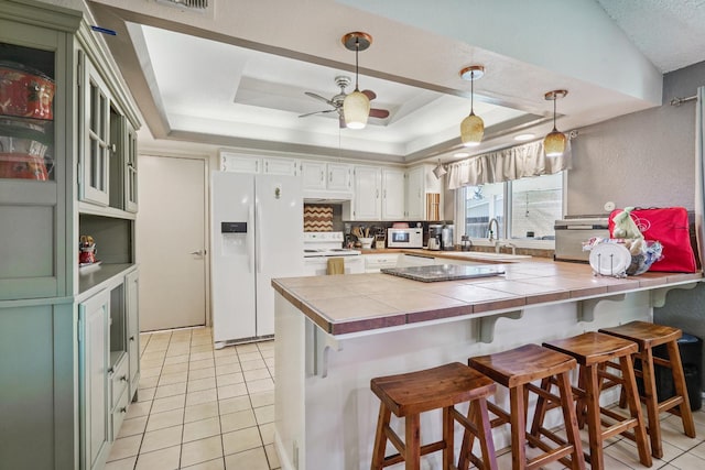 11736 Waverly Rd, Madera, CA 93636 - kitchen with white appliances, a peninsula, a tray ceiling, tile countertops, and light tile patterned floors
