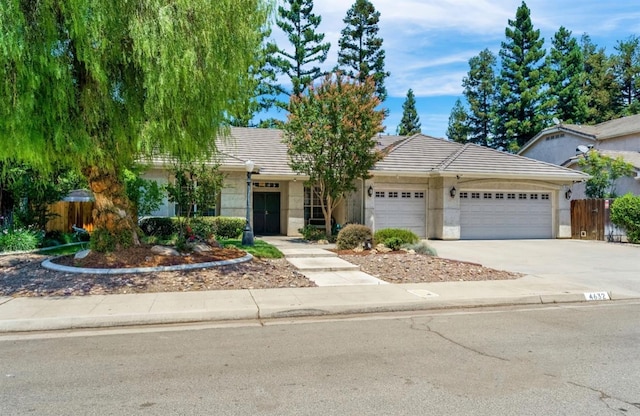 4632 W Minarets Ave, Fresno, CA 93722 - view of front facade featuring an attached garage, concrete driveway, a tile roof, and stucco siding