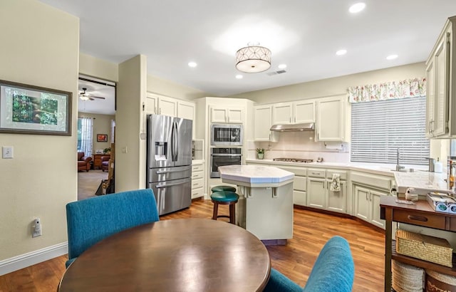 4632 W Minarets Ave, Fresno, CA 93722 - kitchen featuring appliances with stainless steel finishes, under cabinet range hood, a kitchen island, a ceiling fan, and tasteful backsplash