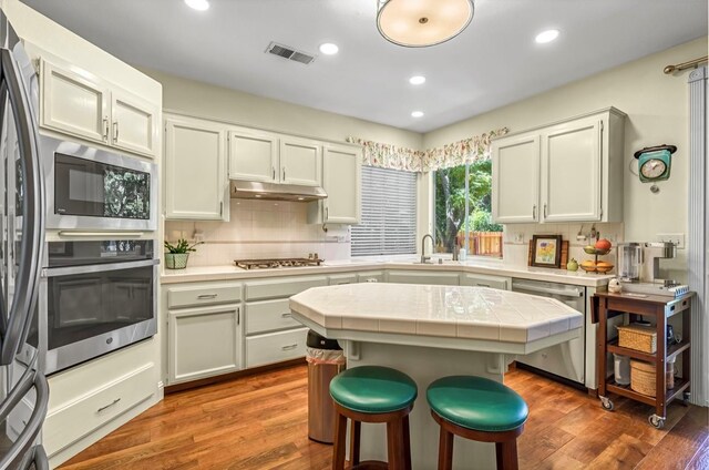 4632 W Minarets Ave, Fresno, CA 93722 - kitchen with appliances with stainless steel finishes, tile counters, wood finished floors, decorative backsplash, and recessed lighting