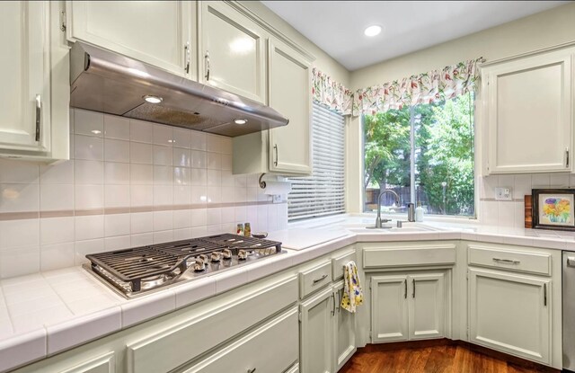 4632 W Minarets Ave, Fresno, CA 93722 - kitchen featuring under cabinet range hood, tile counters, stainless steel appliances, backsplash, and dark wood-style flooring
