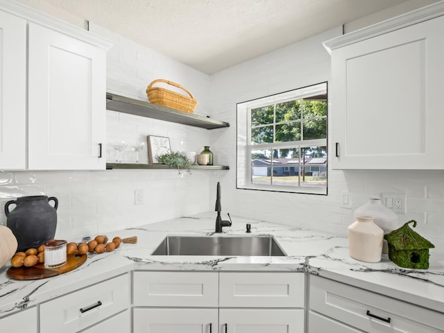3844 E Holland Ave, Fresno, CA 93726 - kitchen featuring backsplash, white cabinetry, light stone counters, and a textured ceiling
