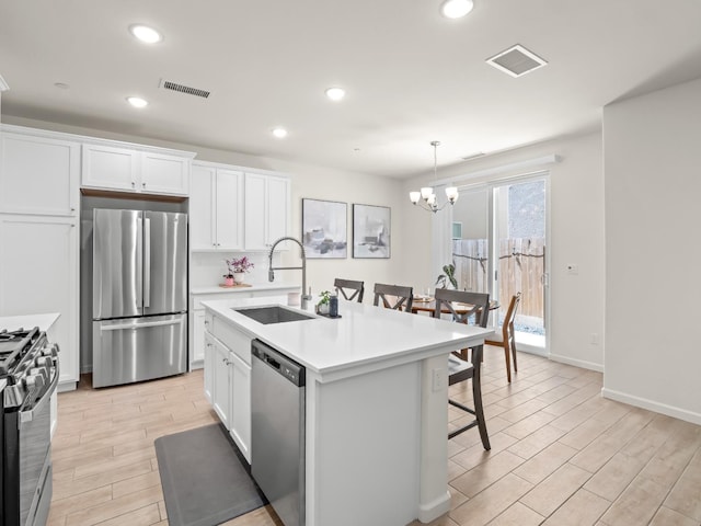 6274 E Riesling Dr, Fresno, CA 93727 - kitchen featuring stainless steel appliances, a breakfast bar area, white cabinetry, light countertops, and a chandelier