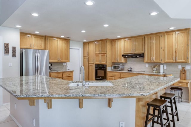 3084 Magnolia Ave, Clovis, CA 93611 - kitchen featuring black appliances, under cabinet range hood, light tile patterned flooring, a kitchen breakfast bar, and recessed lighting