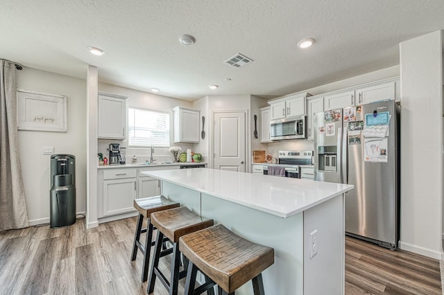 2012 Richard Ave, Sanger, CA 93657 - kitchen featuring stainless steel appliances, a kitchen breakfast bar, a center island, white cabinetry, and light wood-style flooring