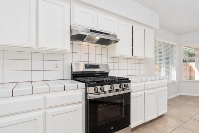 5647 N Tracy Ave, Fresno, CA 93722 - kitchen featuring stainless steel gas range, tile counters, under cabinet range hood, backsplash, and white cabinets