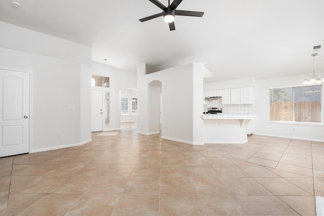 5647 N Tracy Ave, Fresno, CA 93722 - unfurnished living room featuring ceiling fan, a chandelier, arched walkways, light tile patterned flooring, and plenty of natural light
