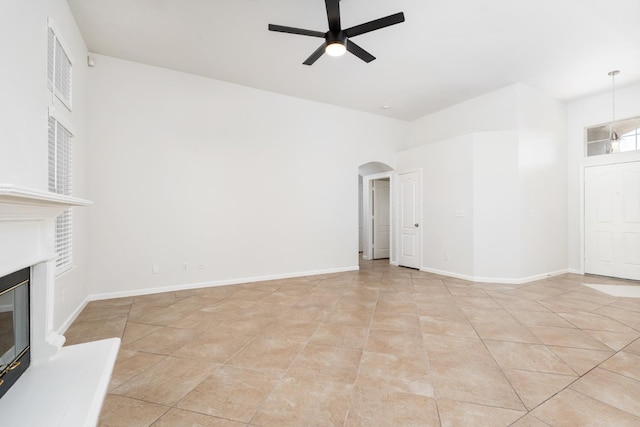 5647 N Tracy Ave, Fresno, CA 93722 - unfurnished living room featuring ceiling fan, arched walkways, a glass covered fireplace, and light tile patterned floors