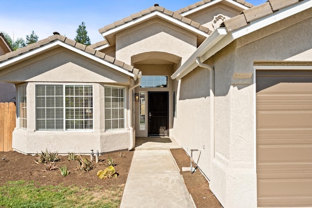 5647 N Tracy Ave, Fresno, CA 93722 - doorway to property with stucco siding, a tiled roof, and a garage