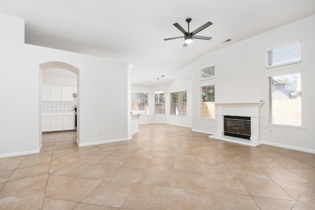 5647 N Tracy Ave, Fresno, CA 93722 - unfurnished living room with a ceiling fan, a glass covered fireplace, vaulted ceiling, plenty of natural light, and light tile patterned floors
