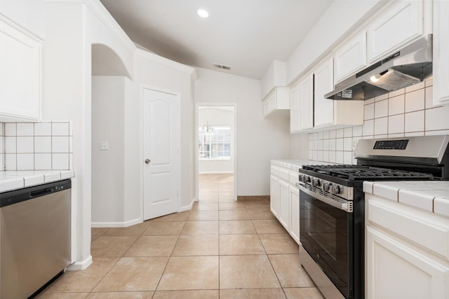 5647 N Tracy Ave, Fresno, CA 93722 - kitchen with appliances with stainless steel finishes, under cabinet range hood, tile counters, vaulted ceiling, and tasteful backsplash