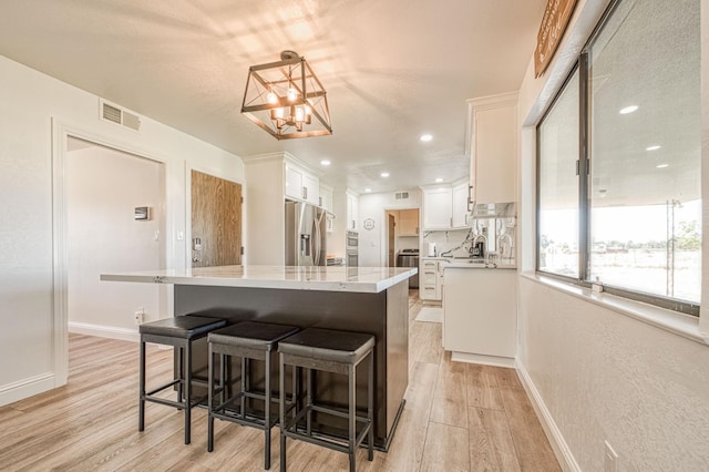 3377 N Bryan Ave, Fresno, CA 93723 - kitchen featuring stainless steel appliances, light wood finished floors, white cabinets, a chandelier, and a center island