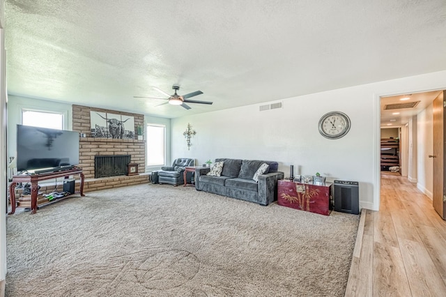3377 N Bryan Ave, Fresno, CA 93723 - living area featuring light wood-style floors, a ceiling fan, a brick fireplace, and a textured ceiling
