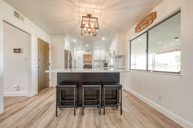 3377 N Bryan Ave, Fresno, CA 93723 - kitchen featuring stainless steel fridge, light wood-style flooring, white cabinets, light countertops, and a breakfast bar