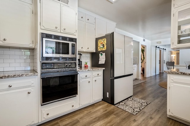 6372 N Benedict Ave, Fresno, CA 93711 - kitchen with black oven, freestanding refrigerator, stainless steel microwave, white cabinets, and backsplash