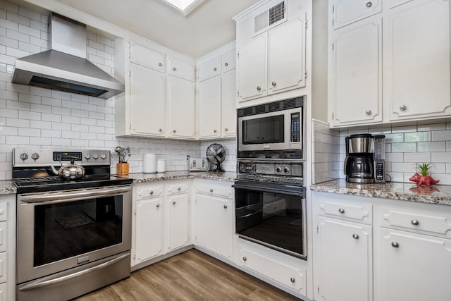 6372 N Benedict Ave, Fresno, CA 93711 - kitchen featuring wall chimney range hood, stainless steel appliances, white cabinets, and light wood finished floors