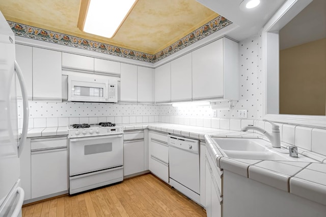 1210 E Province Dr, Fresno, CA 93720 - kitchen featuring white appliances, tile countertops, white cabinetry, light wood-style floors, and backsplash