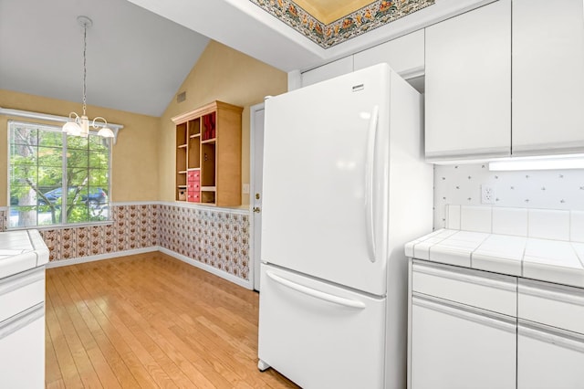 1210 E Province Dr, Fresno, CA 93720 - kitchen with freestanding refrigerator, tile counters, white cabinets, light wood finished floors, and lofted ceiling