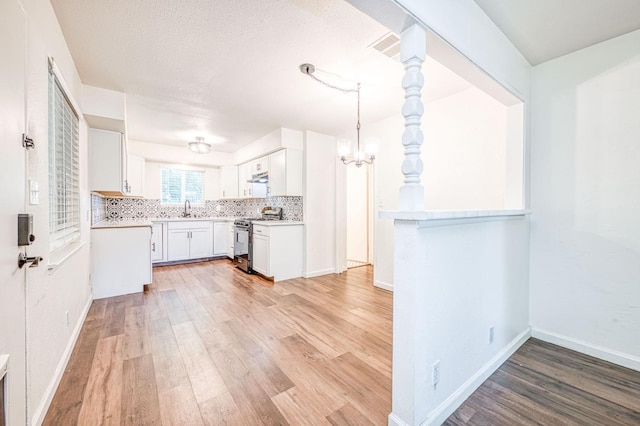 1821 W Lansing Way, Fresno, CA 93705 - kitchen with stainless steel range oven, light wood-style flooring, tasteful backsplash, light countertops, and white cabinetry