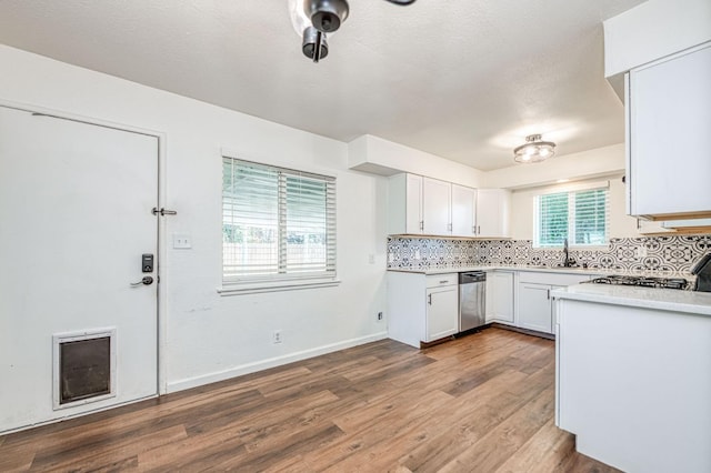 1821 W Lansing Way, Fresno, CA 93705 - kitchen featuring stainless steel dishwasher, backsplash, light countertops, dark wood finished floors, and white cabinets