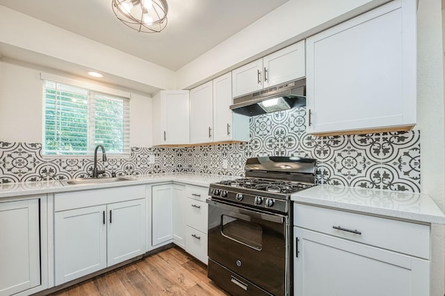 1821 W Lansing Way, Fresno, CA 93705 - kitchen featuring black gas stove, under cabinet range hood, light wood finished floors, white cabinetry, and decorative backsplash
