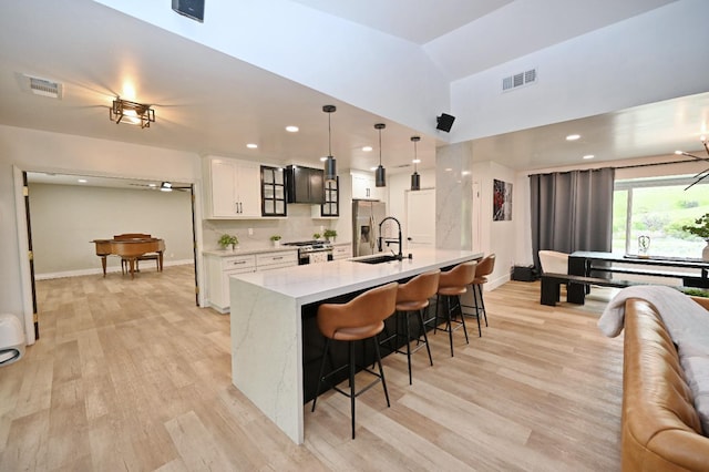 25190 Elwood Rd, Sanger, CA 93657 - kitchen featuring stainless steel appliances, a kitchen bar, white cabinetry, light wood-type flooring, and a center island with sink