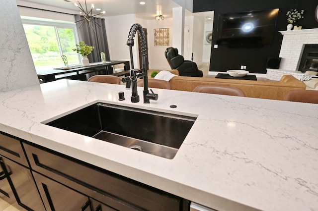 25190 Elwood Rd, Sanger, CA 93657 - kitchen with open floor plan, light stone countertops, a chandelier, and a fireplace