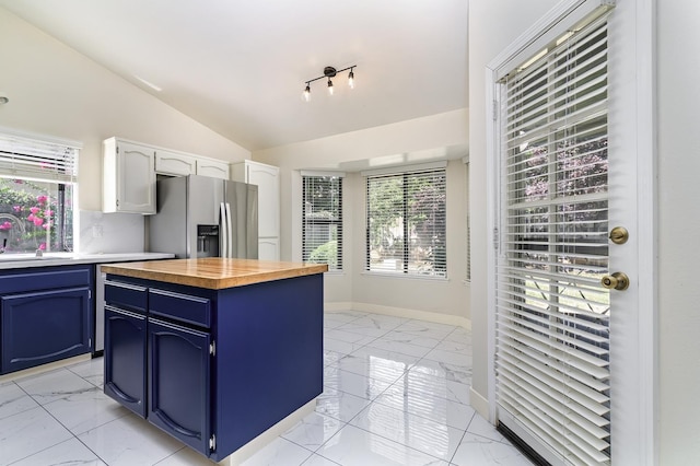 6447 N Vagedes Ave, Fresno, CA 93711 - kitchen featuring stainless steel fridge, blue cabinets, light marble finish floors, wooden counters, and vaulted ceiling