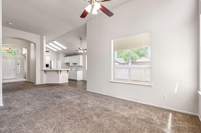 5811 W Beechwood Ave, Fresno, CA 93722 - unfurnished living room featuring ceiling fan, arched walkways, plenty of natural light, dark carpet, and high vaulted ceiling