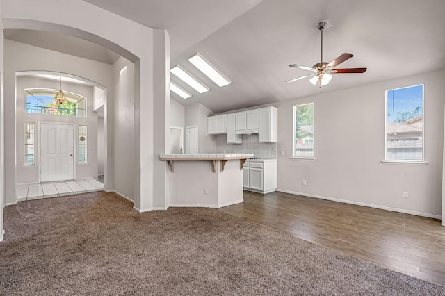 5811 W Beechwood Ave, Fresno, CA 93722 - kitchen featuring vaulted ceiling, dark colored carpet, a breakfast bar area, open floor plan, and white cabinetry