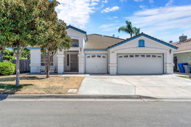 5811 W Beechwood Ave, Fresno, CA 93722 - view of front of house with driveway, an attached garage, stucco siding, and a tile roof