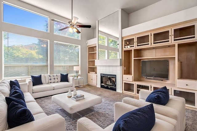 5811 W Beechwood Ave, Fresno, CA 93722 - carpeted living room with a ceiling fan, a tile fireplace, a towering ceiling, and built in shelves
