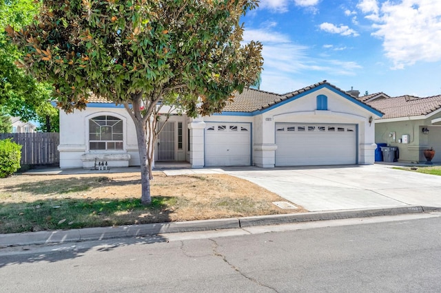5811 W Beechwood Ave, Fresno, CA 93722 - view of front of home featuring a garage, stucco siding, concrete driveway, and a tile roof