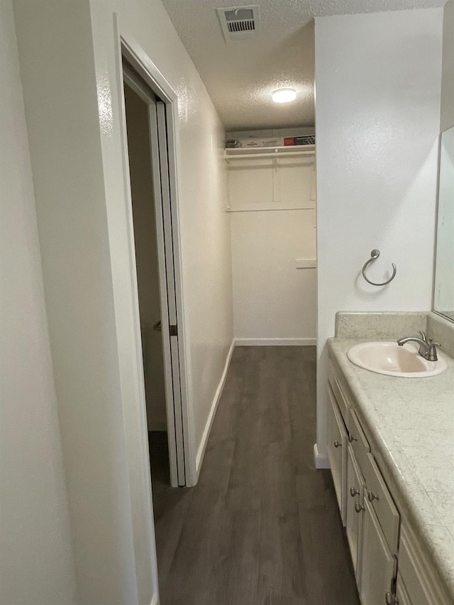1027 W Dakota Ave Unit 102, Fresno, CA 93705 - bathroom featuring vanity, wood finished floors, a textured ceiling, and a walk in closet