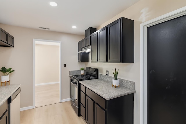 1402 E Shields Ave, Fresno, CA 93704 - kitchen with stainless steel gas stove, under cabinet range hood, dishwashing machine, light wood-style floors, and light countertops