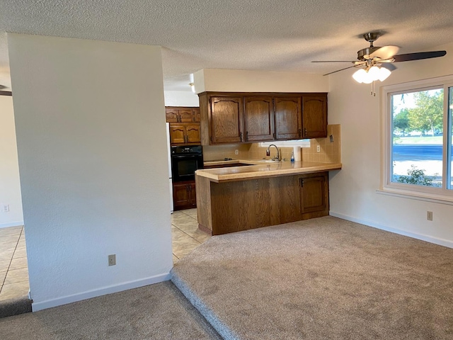12173 Rd 36, Madera, CA 93636 - kitchen featuring black oven, a peninsula, light countertops, light colored carpet, and a textured ceiling