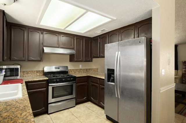 5051 E Lewis Ave, Fresno, CA 93727 - kitchen featuring stainless steel appliances, under cabinet range hood, dark brown cabinetry, light tile patterned floors, and light countertops