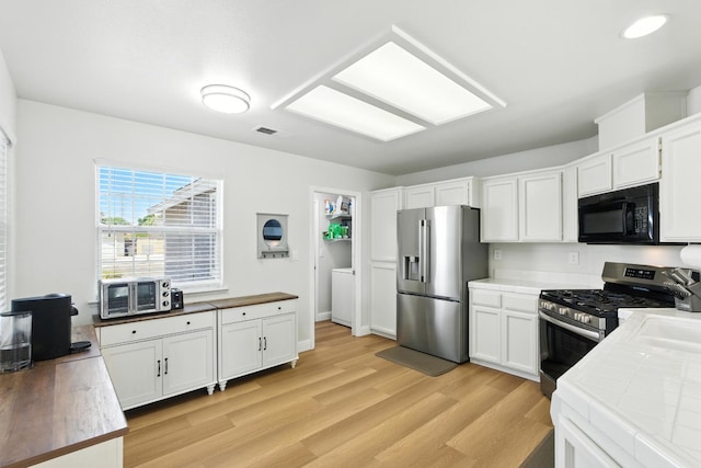 6431 E Inyo St, Fresno, CA 93727 - kitchen with appliances with stainless steel finishes, tile countertops, light wood-style flooring, and white cabinets