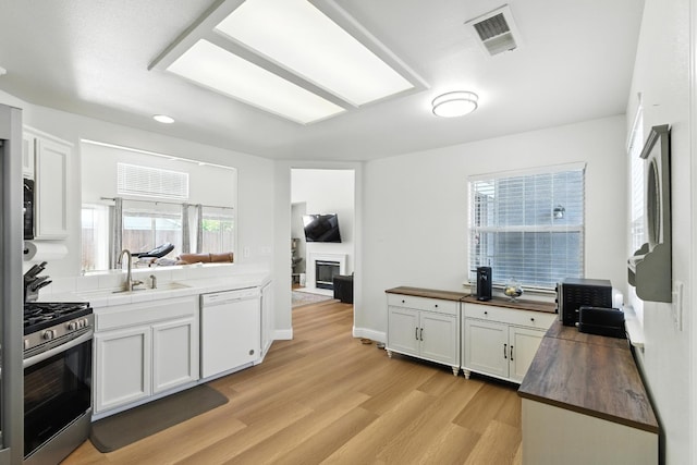 6431 E Inyo St, Fresno, CA 93727 - kitchen featuring dishwasher, stainless steel gas range, light wood finished floors, and a glass covered fireplace