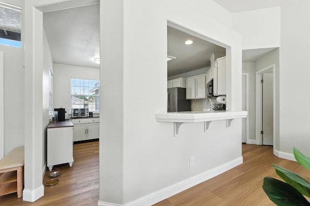 6431 E Inyo St, Fresno, CA 93727 - kitchen with stainless steel appliances, wood finished floors, a breakfast bar area, white cabinets, and recessed lighting