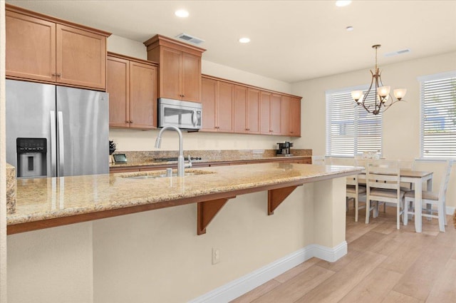 2481 S Via Versilia Dr, Fresno, CA 93727 - kitchen featuring appliances with stainless steel finishes, a chandelier, light wood-style floors, light stone counters, and recessed lighting