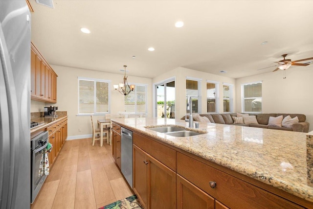 2481 S Via Versilia Dr, Fresno, CA 93727 - kitchen with appliances with stainless steel finishes, light wood finished floors, light stone counters, brown cabinets, and pendant lighting